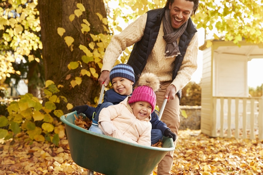 family playing outside in the leaves after scheduling their fall HVAC maintenance