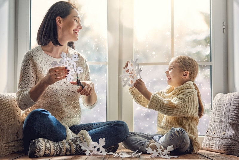 Mother and daughter making snowflake decorations.